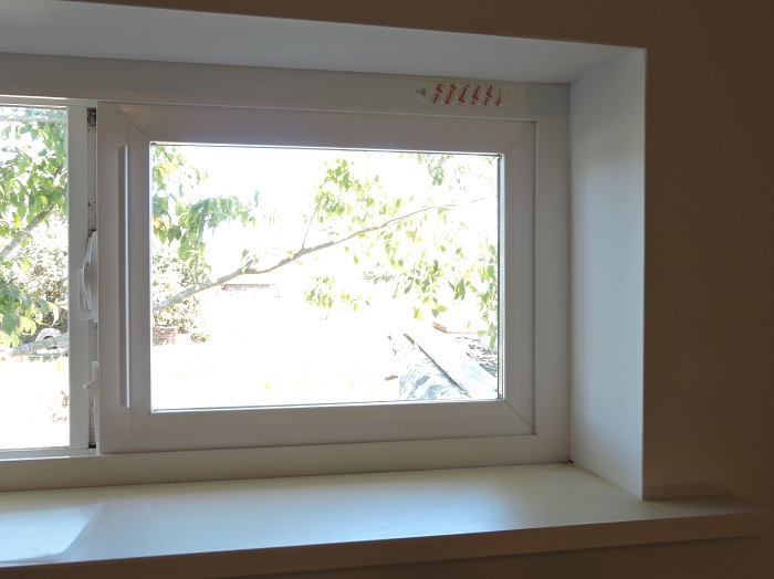 window with command strip attached to the top of frame