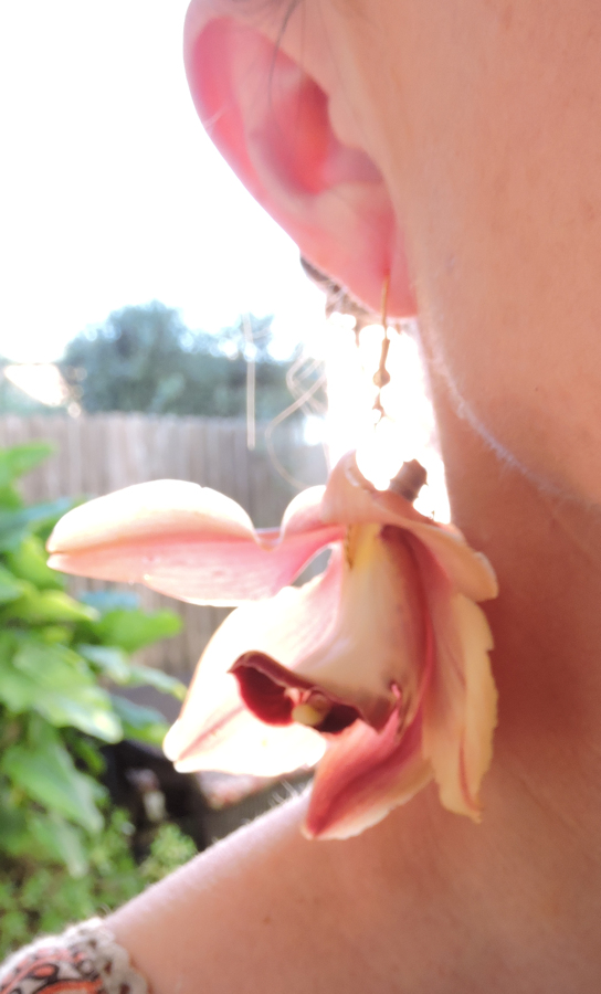pink orchid earring hanging from ear