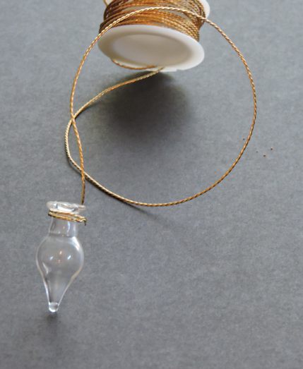 gold wire wrapped around tiny glass tear shaped vial