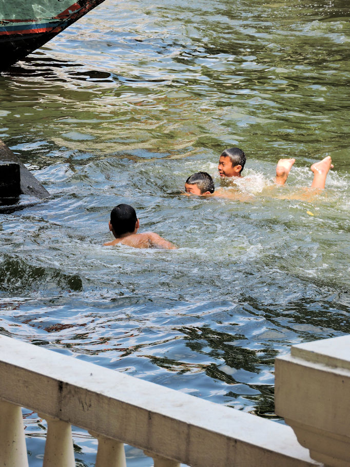 three kids swiming in Bangkok canal