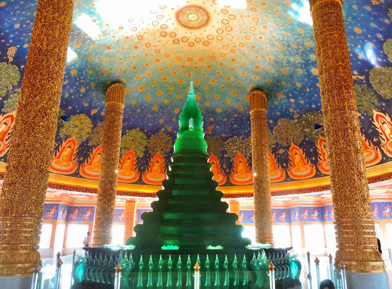 interior of ornate stupa with green crystal and gold pillars