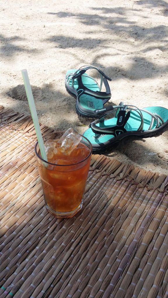 sandals and icetea on beach sand