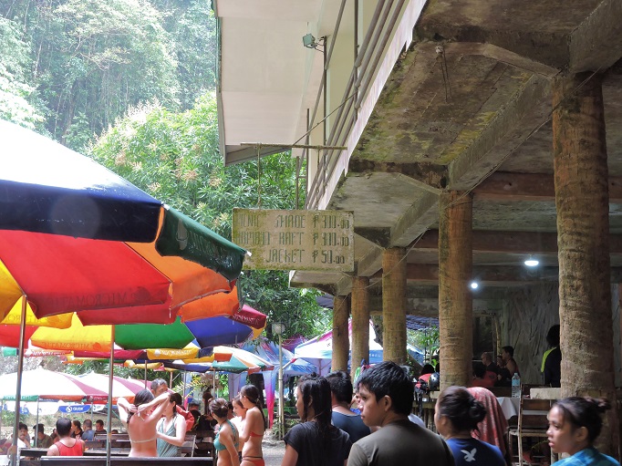 lots of people and table umbrellas at Kawasan with sign for renting