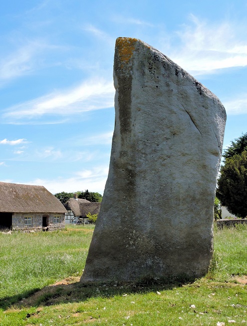 one large stone in front of thatched barn