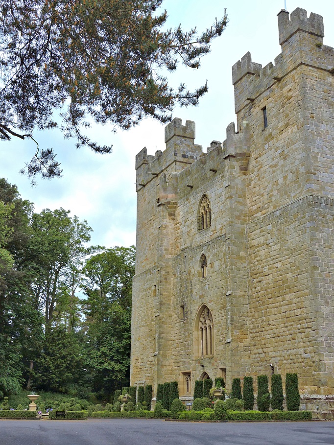 side angle view of Langley castle with trees and hedges