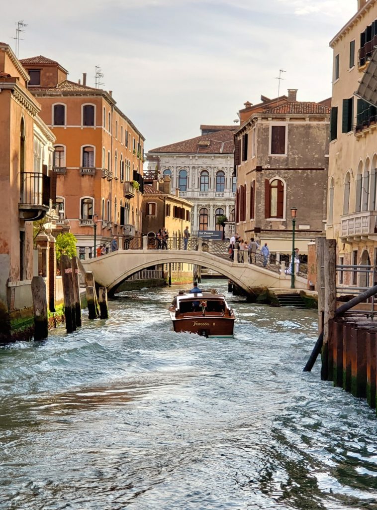 boat under bridge along canal venice italy