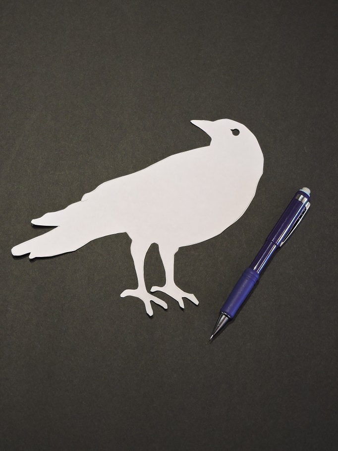 using stencil to trace crow onto black paper