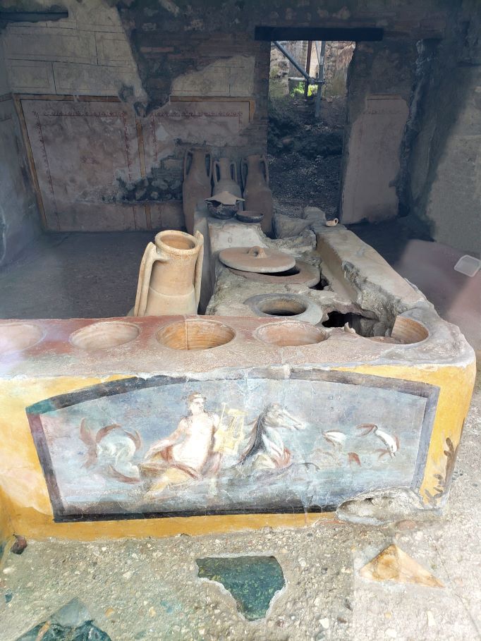 paintings and amphorae in ancient fast food shop of pompeii