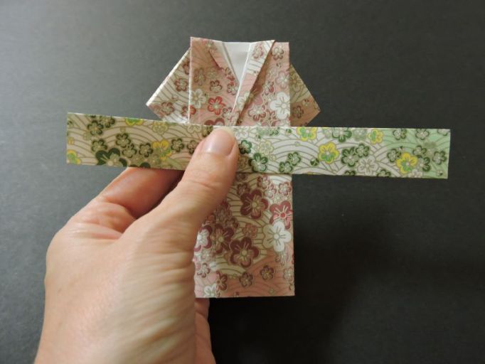 wrapping green paper obi belt around paper kimono