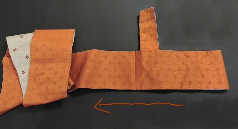 arrow illustrating next step in folding obi
