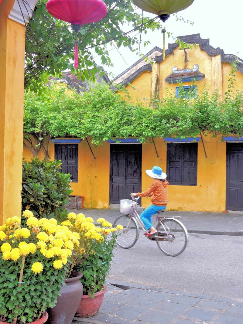 riding bicycle through Hoi An past yellow buildings