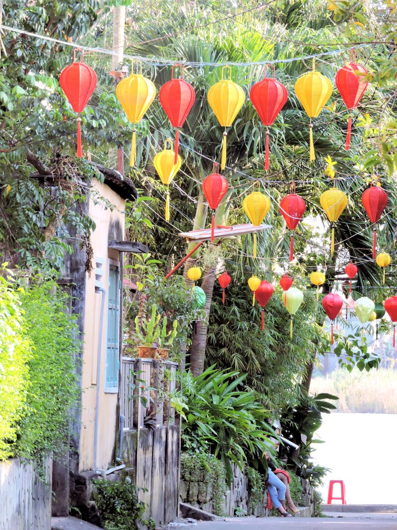 yellow and red lanterns strung across street leading to river