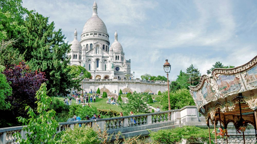 white basilica on top of hill with trees and carousel