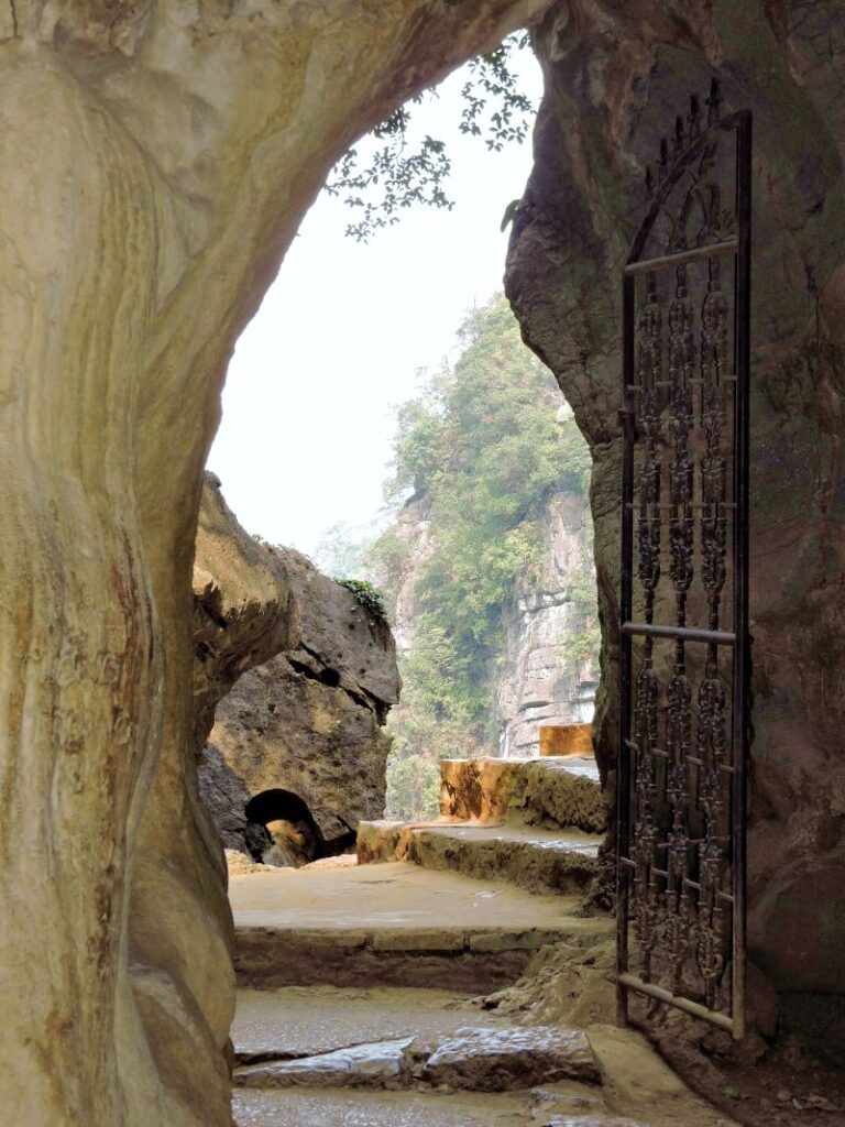 inside temple pagoda cave looking out at karst cliffs and steps