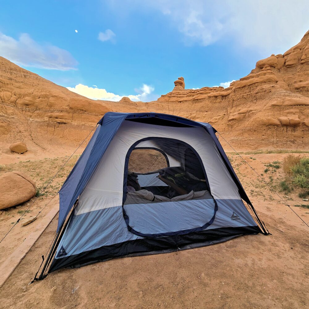 blue tent with sandstone cliffs behind it