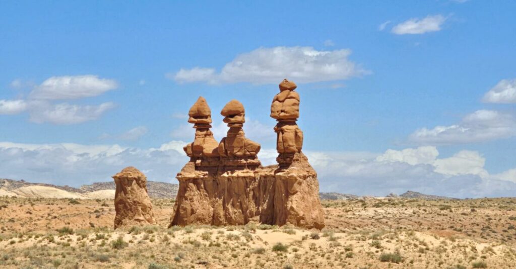large rock formation with three pillars in dessert backdrop